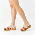 Menorquinas con cuña de piel con pala trenzada con una combinación de colores de marrón, naranja, amarillo y piso de color caramelo puestas en los pies de una modelo vista desde el ángulo lateral