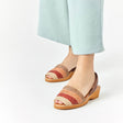 Sandalias menorquinas con una combinación de colores otoñales puestas en los pies de una mujer vistas desde un ángulo frontal lateral