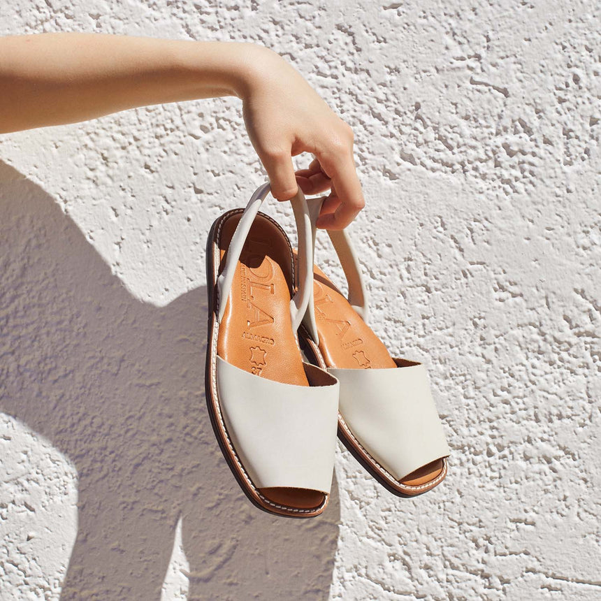 Menorquinas planas de piel de color blanco roto mostradas por la modelo