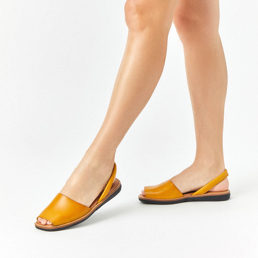 Menorquinas planas de piel de color panama puestas en los pies de una modelo vista dese el ángulo frontal