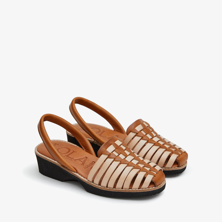 Sandalia menorquina con cuña con una combinación trenzada color arena y avellana vista desde un ángulo lateral