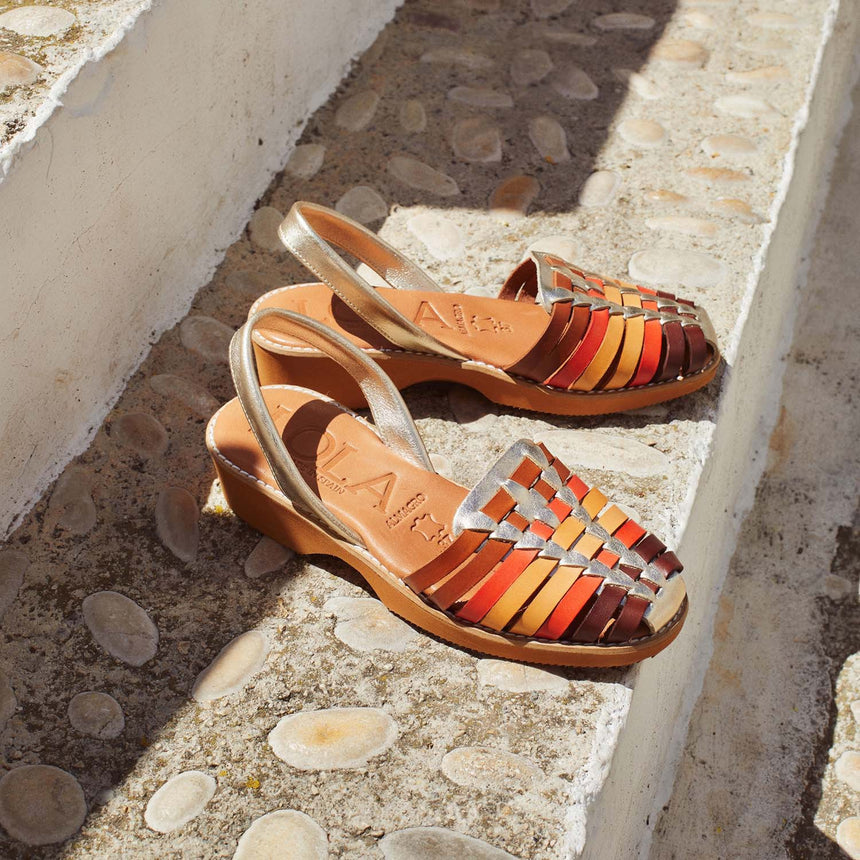Menorquinas con cuña de piel con pala trenzada con una combinación de colores de marrón, naranja, amarillo y piso de color caramelo vista creativa desde el ángulo frontal