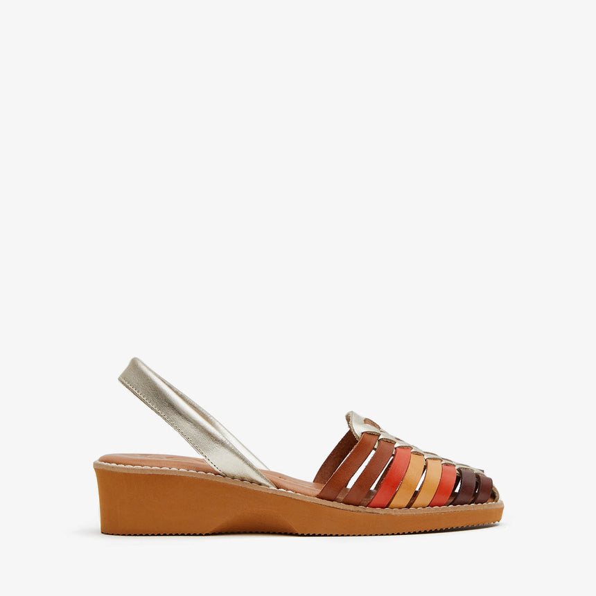 Menorquinas con cuña de piel con pala trenzada con una combinación de colores de marrón, naranja, amarillo y piso de color caramelo vista desde el lateral