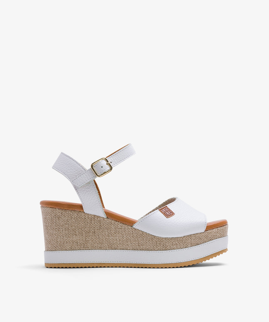 Sandalias de piel plana de color blanco con plataforma con una tira de color blanco vista desde el lateral